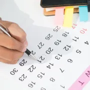 Mano marcando una fecha en un calendario, ilustrando el proceso para agendar una cita con un oftalmólogo en León Gto.