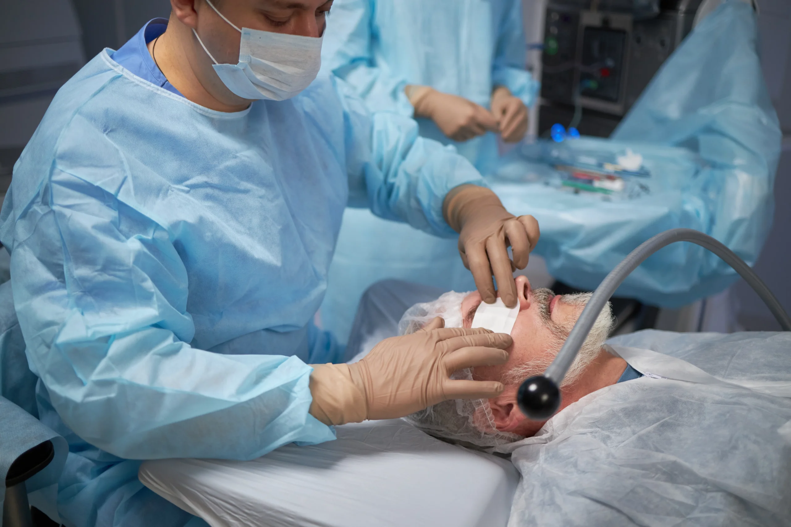 Paciente masculino adulto siendo atendido por el cirujano inmediatamente después de la exitosa cirugía de cataratas, con el ojo vendado.