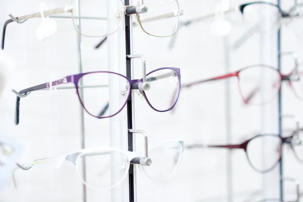 Close up of purple and white fashionable eyewear frames featuring ophthalmic lenses in a clean professional medical setting